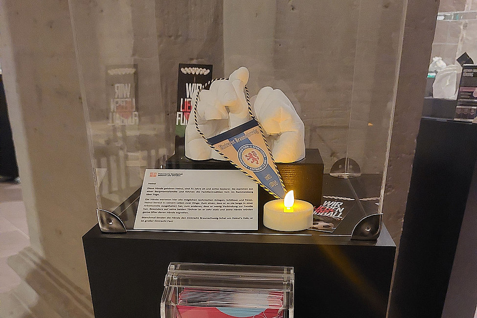 Gipsabdruck eines Händepaars mit Wimpel und Kerze in Ausstellungsvitrine